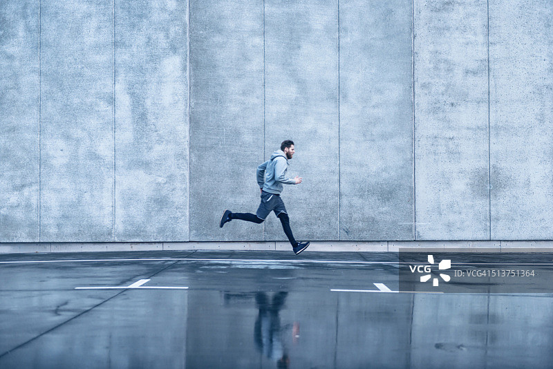 男人在水泥建筑前快速奔跑图片素材