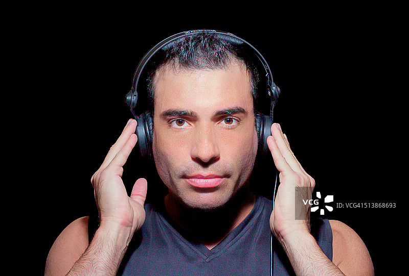 男人戴着耳机听音乐，正面视角图片素材