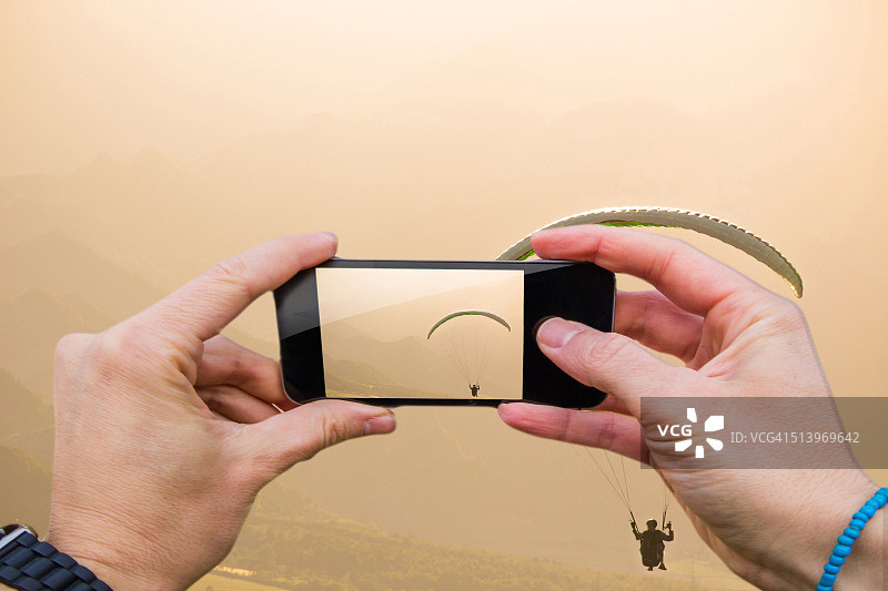 男人用手机在比利牛斯山脉以第一视角拍摄滑翔伞图片素材