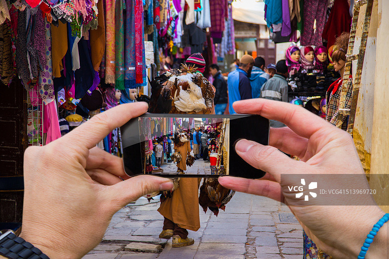 旅行男人在摩洛哥菲斯彩色麦地那街头用智能手机拍照图片素材