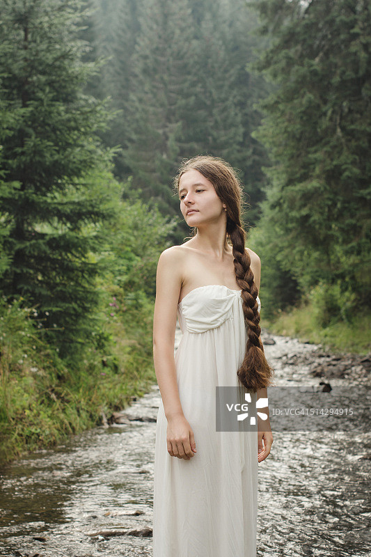 年轻女子赤脚穿过山间河流图片素材