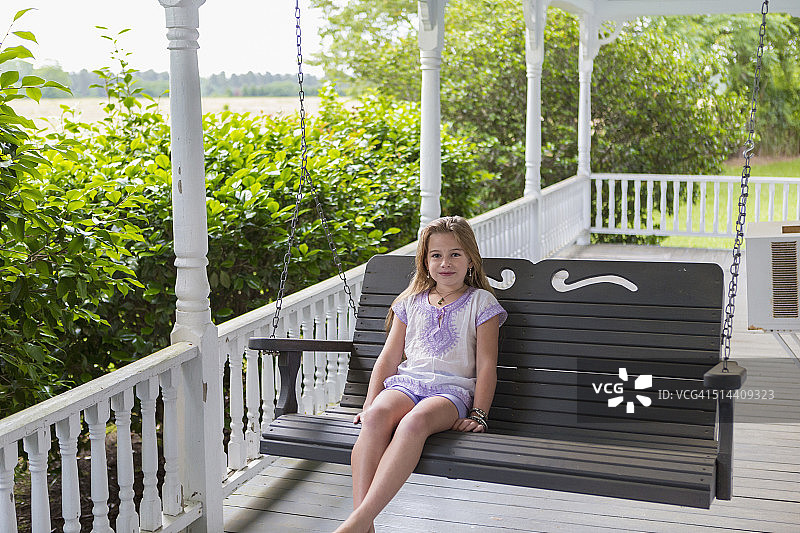 白人女孩在门廊的秋千上放松图片素材