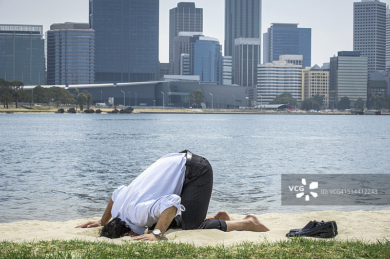 在澳大利亚西澳大利亚州珀斯海滩上将头埋在沙子里的西班牙裔商人图片素材