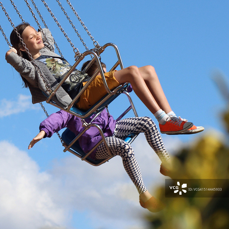 在游乐场的旋转木马上玩耍的两个女孩图片素材