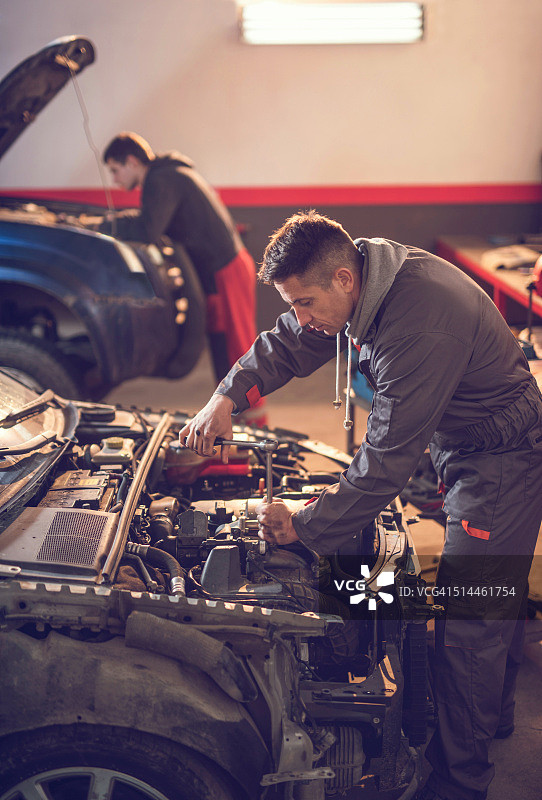 维修人员在汽车修理店使用套筒扳手图片素材