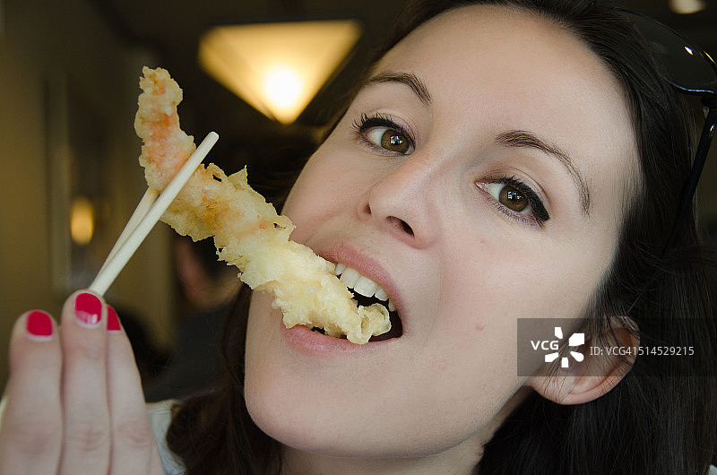 用筷子吃天妇罗炸虾的漂亮女人图片素材