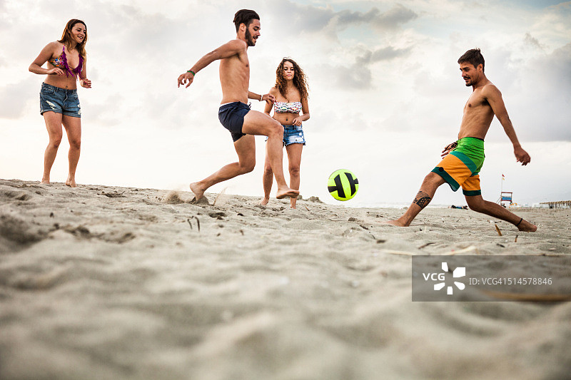 朋友们在海滩度假时踢足球图片素材