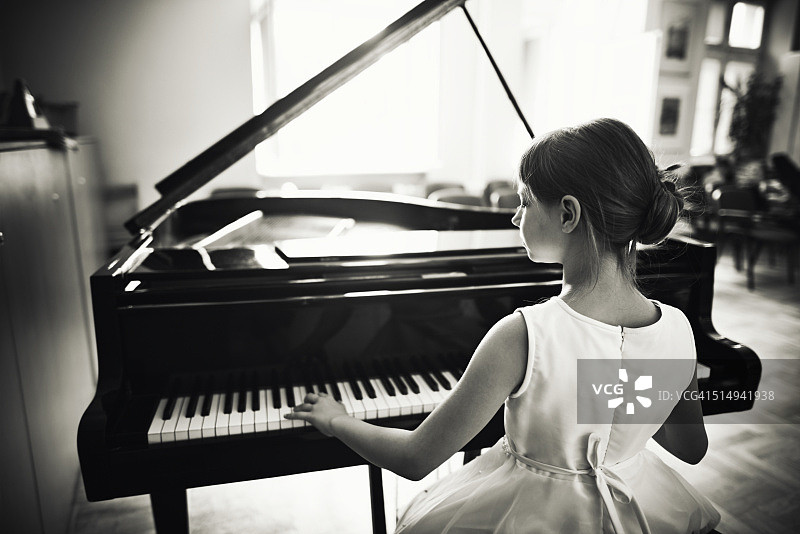 小女孩在三角钢琴上玩耍图片素材