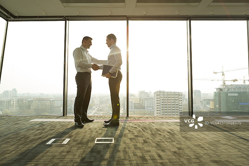 阳光明媚的办公室里握手的两位商人图片素材