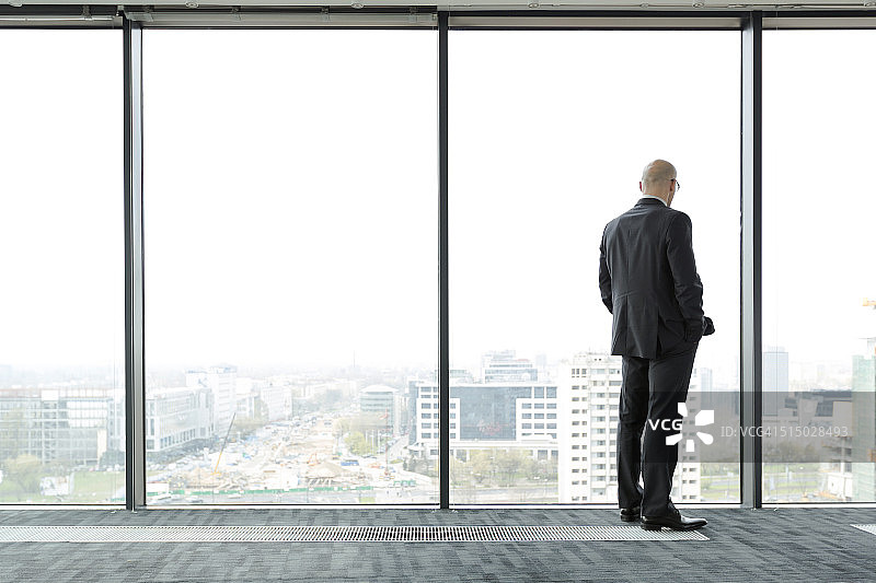 空旷办公室里眺望窗外的商务男士图片素材