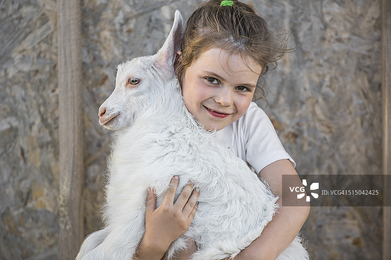户外抱着小山羊的可爱女孩肖像图片素材