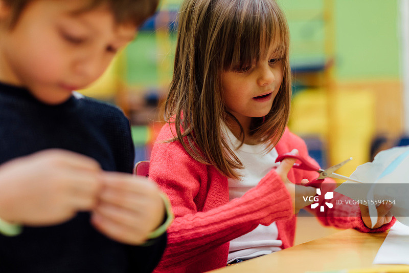 在幼儿园使用剪刀的快乐小女孩图片素材