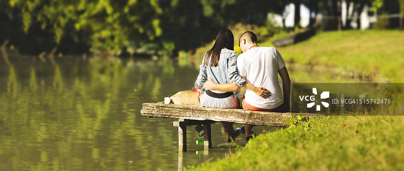 情侣与巴哥犬在公园亲密互动图片素材