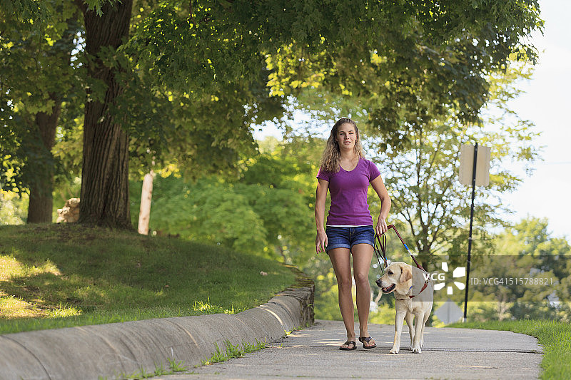 视力障碍的女人在导盲犬的帮助下行走图片素材