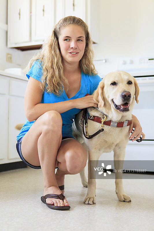 有视觉障碍的妇女在厨房里和她的服务犬图片素材