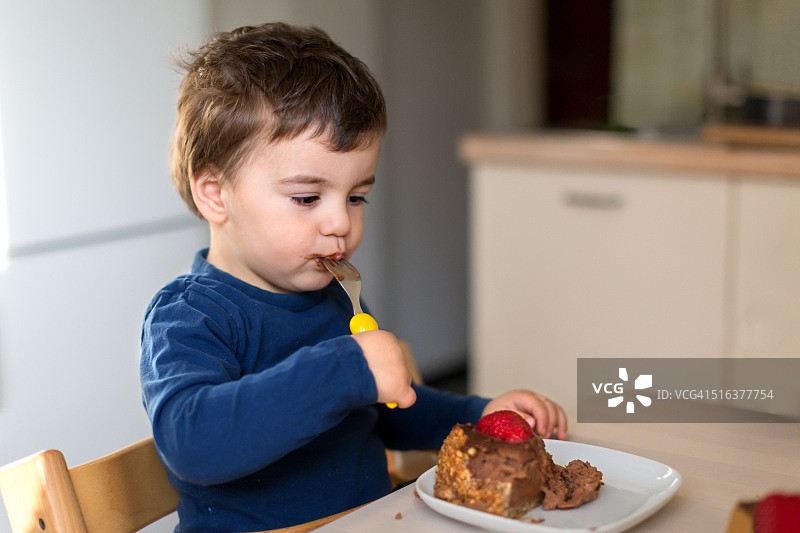 吃巧克力芝士蛋糕的幼儿男孩图片素材