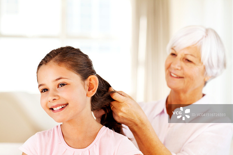 奶奶给孙女编辫子，孙女看向远方图片素材
