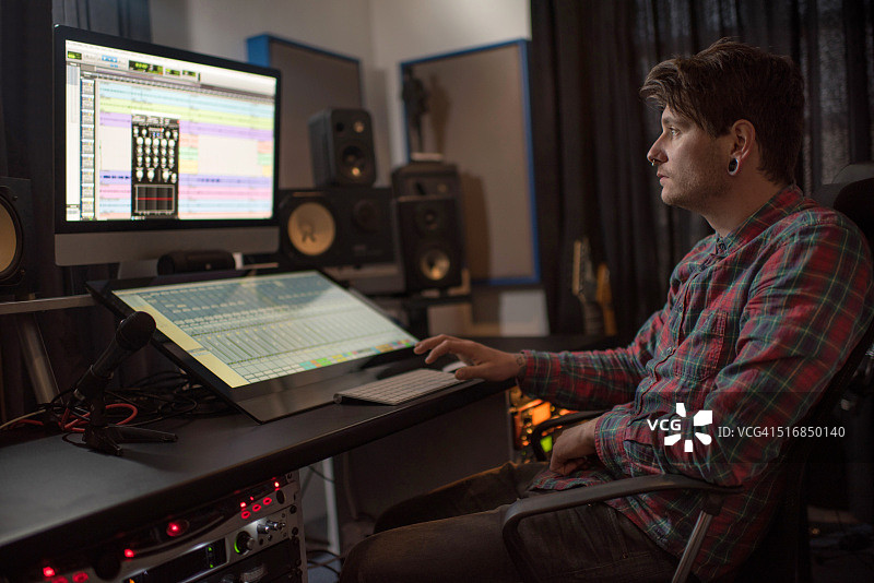 声音工程师在音乐工作室的电脑上作曲。图片素材