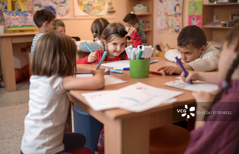 微笑的小女孩和她的朋友们在幼儿园里图片素材