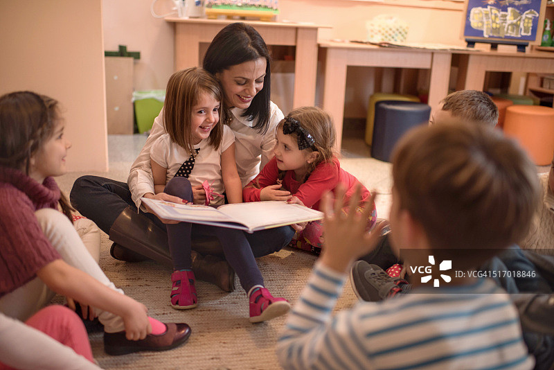 快乐的学龄前老师给一群小孩讲故事图片素材