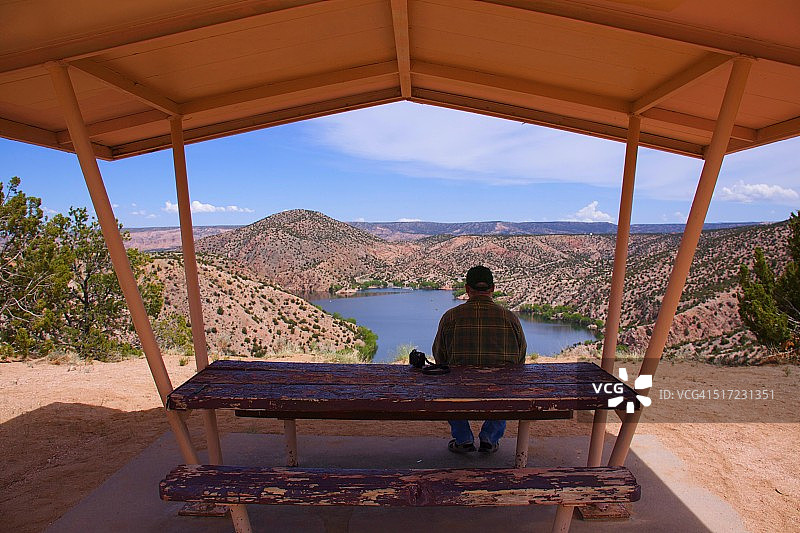 坐在野餐桌遮阳篷下的男人图片素材