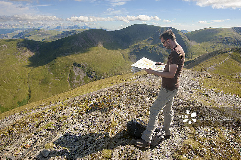 男子在湖区山顶上阅读地图图片素材