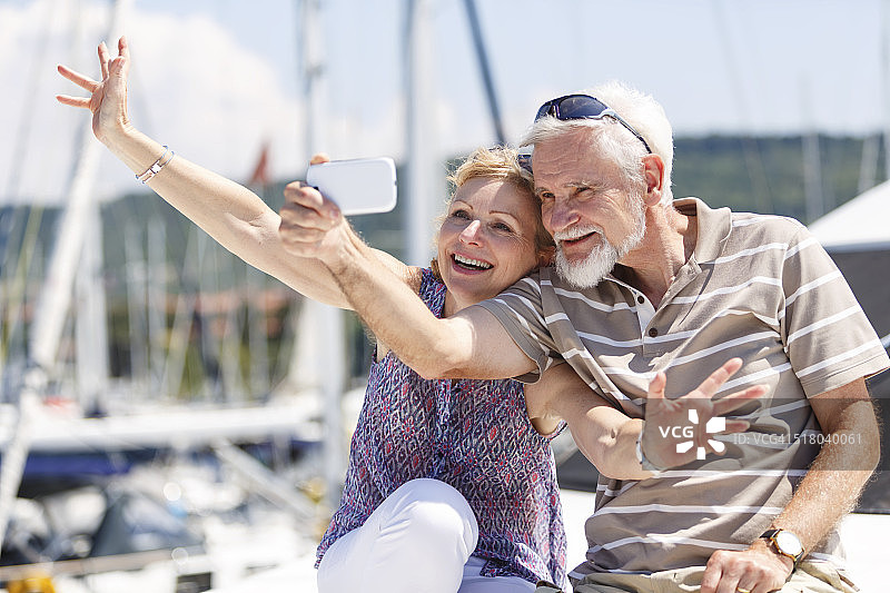 老年夫妇在游艇上玩智能手机图片素材
