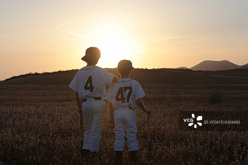 穿棒球服看日落的两个男孩图片素材