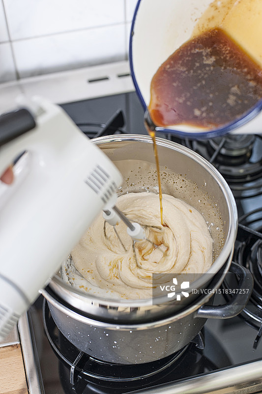 在水浴锅中搅拌打发的蛋白，加入焦糖，高角度拍摄图片素材