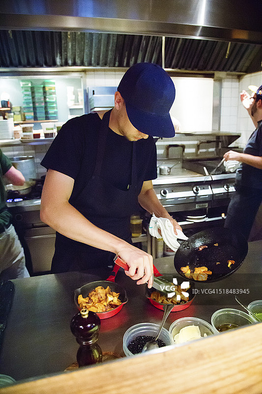 厨师将一锅炒好的鸡油菌蘑菇摆盘图片素材