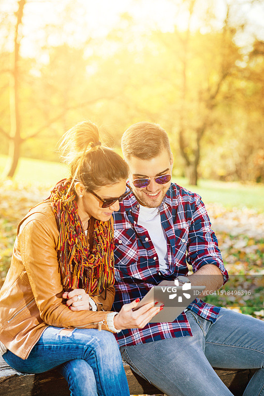 阳光明媚的日子里，情侣使用平板电脑图片素材