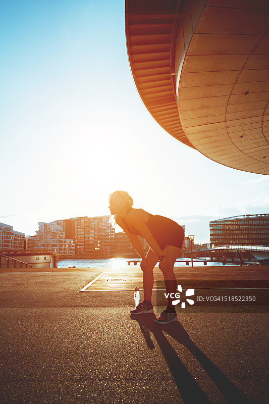 疲惫的跑步女运动员在日落时分休息并补充水分图片素材
