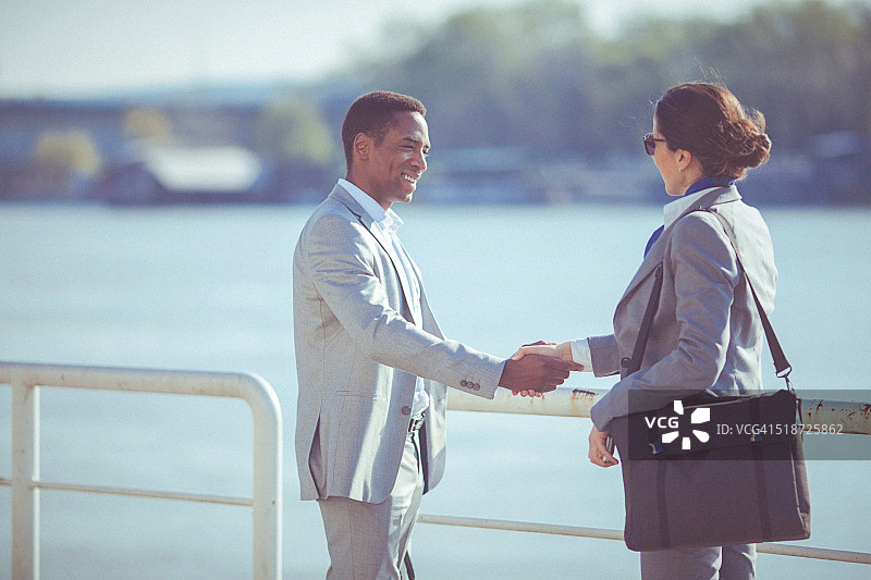 年轻女子和男人在海滨握手会面图片素材