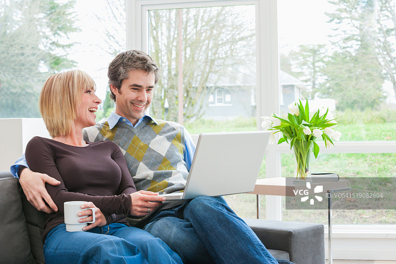 情侣坐在一起使用笔记本电脑图片素材