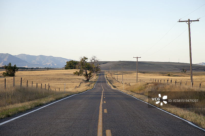 黎明时分穿过草原的空旷道路图片素材