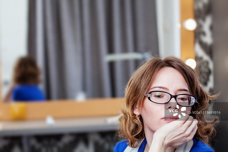 悲伤的女孩背对着镜子坐在美容院里图片素材