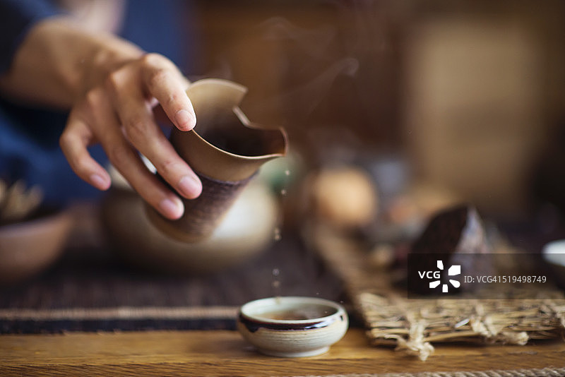 将中国茶倒入陶瓷茶杯中图片素材