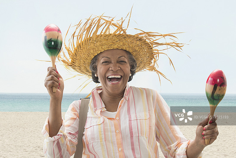 在海滩上演奏沙槌的年长的非裔美国妇女图片素材