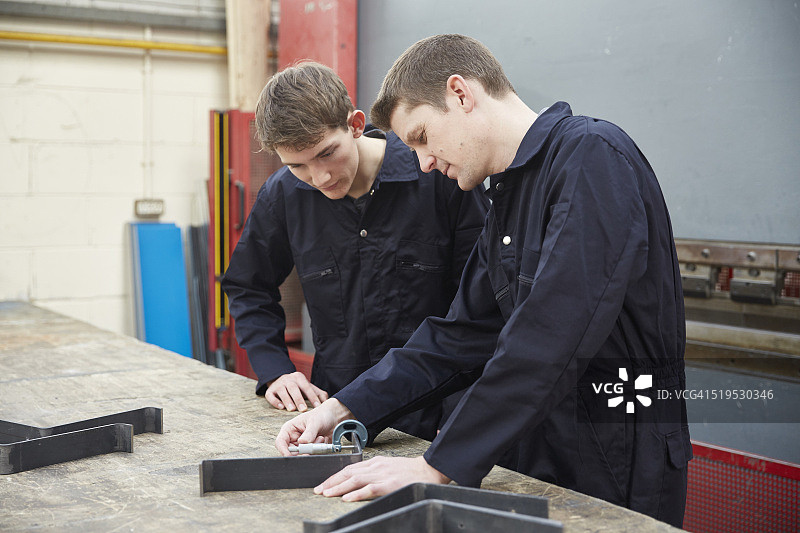 学徒观看工程师在钢铁制造厂的演示图片素材