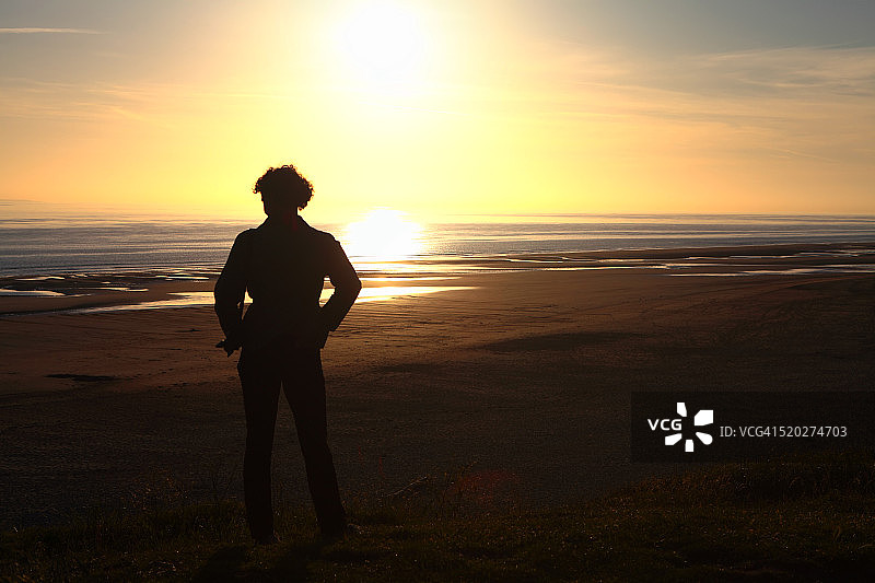 在海滩日落时分的一位女子图片素材