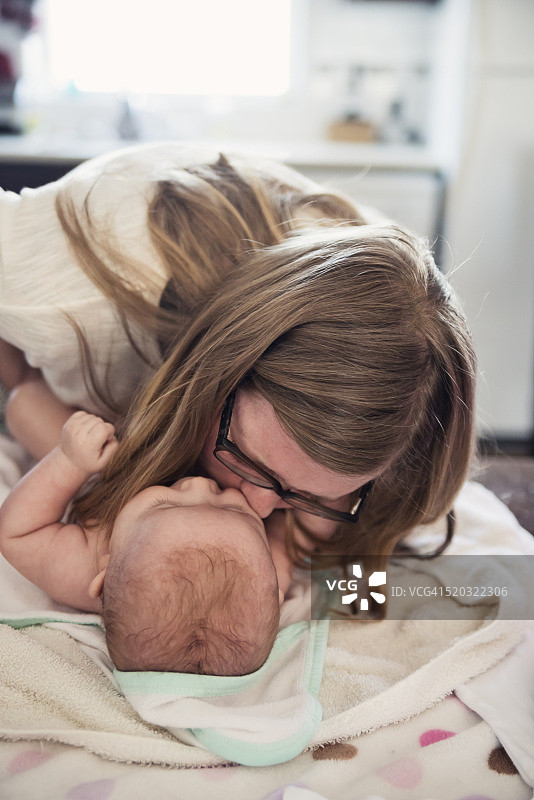 妈妈在厨房洗完澡后亲吻宝宝。图片素材