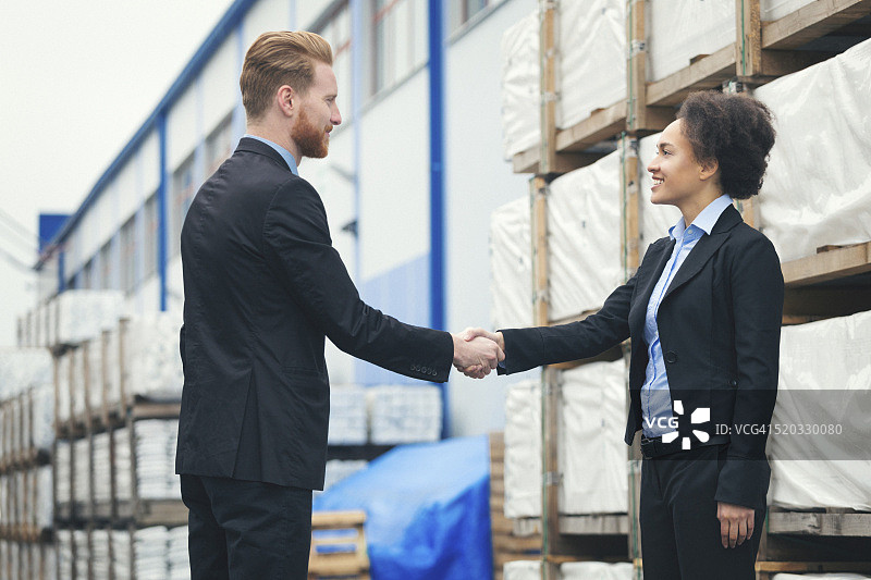 在仓库握手的男女商人图片素材