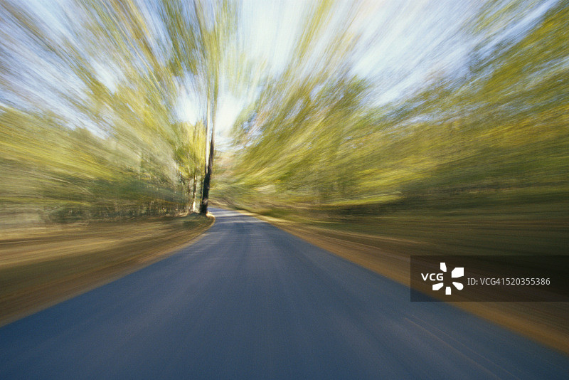 在乡村道路上飞驰而过，树木模糊图片素材