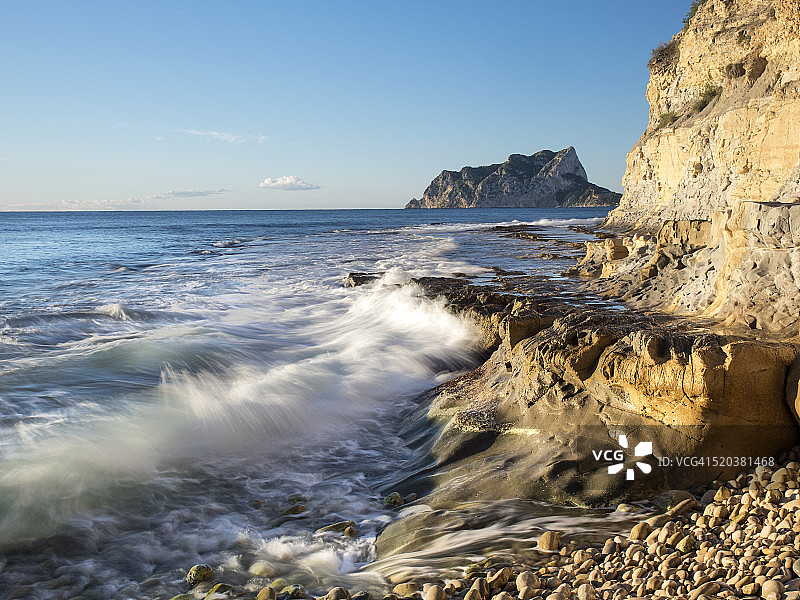阳光照耀下的岩石海岸蓝色天空图片素材
