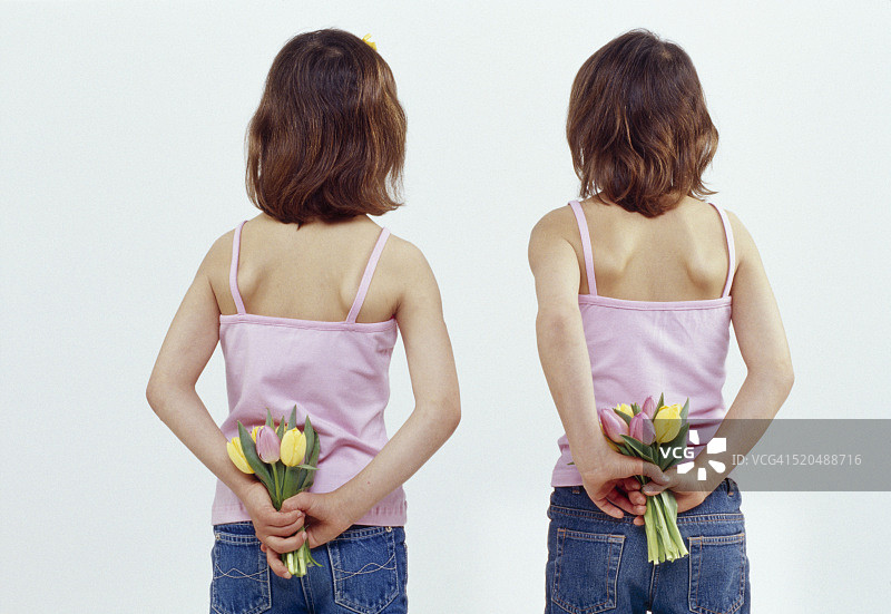 双胞胎姐妹在背后拿着郁金香图片素材