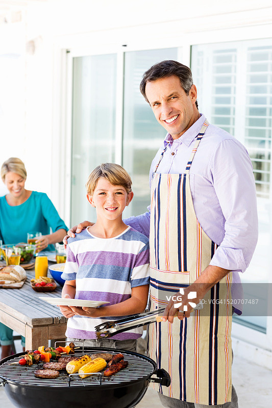 父子在露台烧烤架旁图片素材