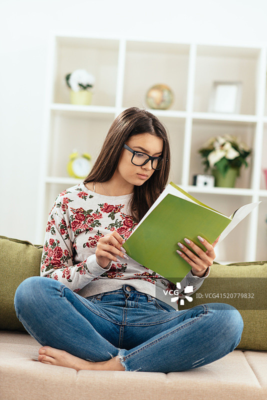 坐在沙发上看杂志的年轻女子肖像图片素材