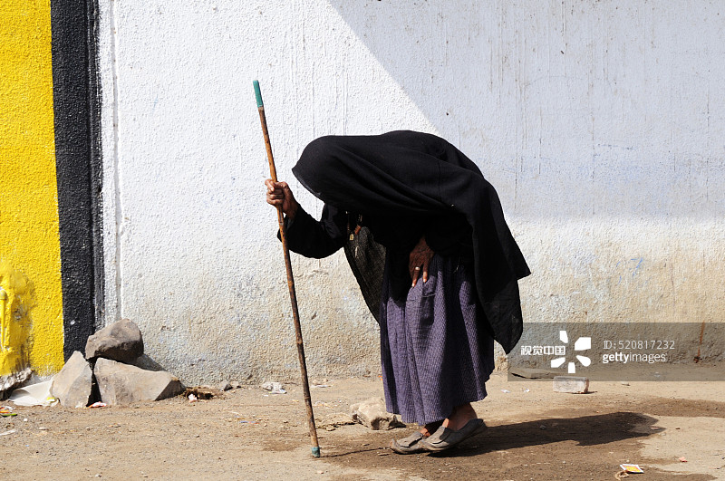 老妇人在印度古吉拉特邦安贾尔附近拄着拐杖行走图片素材