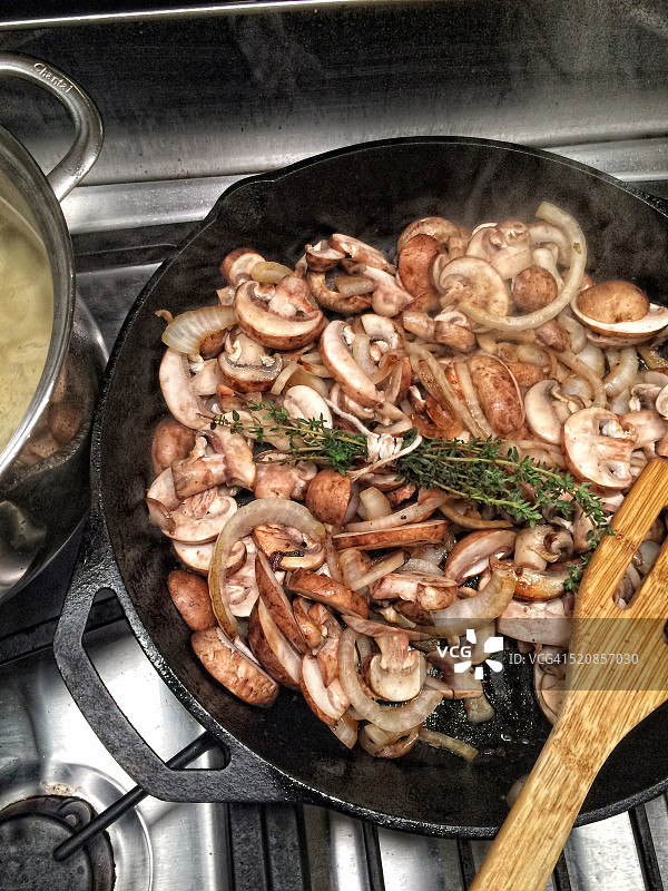 在煎锅中烹饪的蘑菇、香草和洋葱图片素材