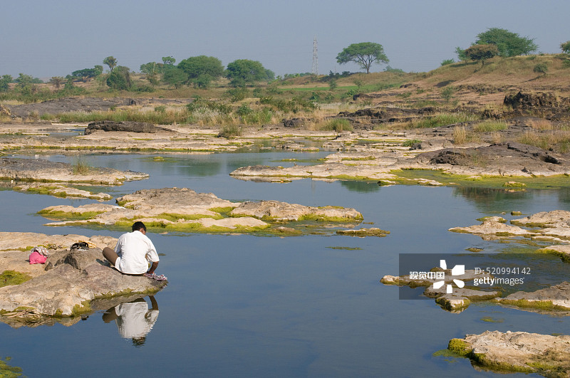 男子在印度马哈拉施特拉邦纳西克戈达瓦里河中洗衣服图片素材